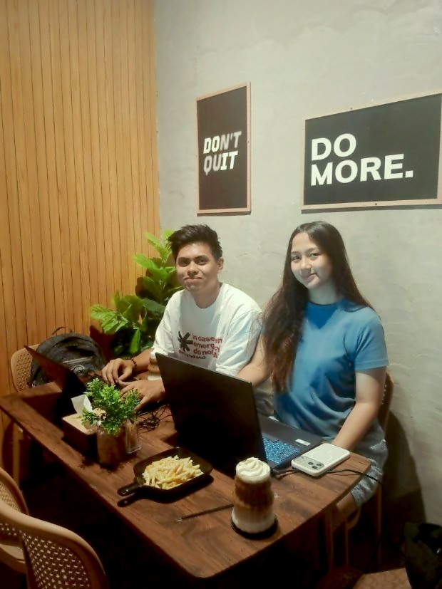 Two customers on laptops under the Do More prints