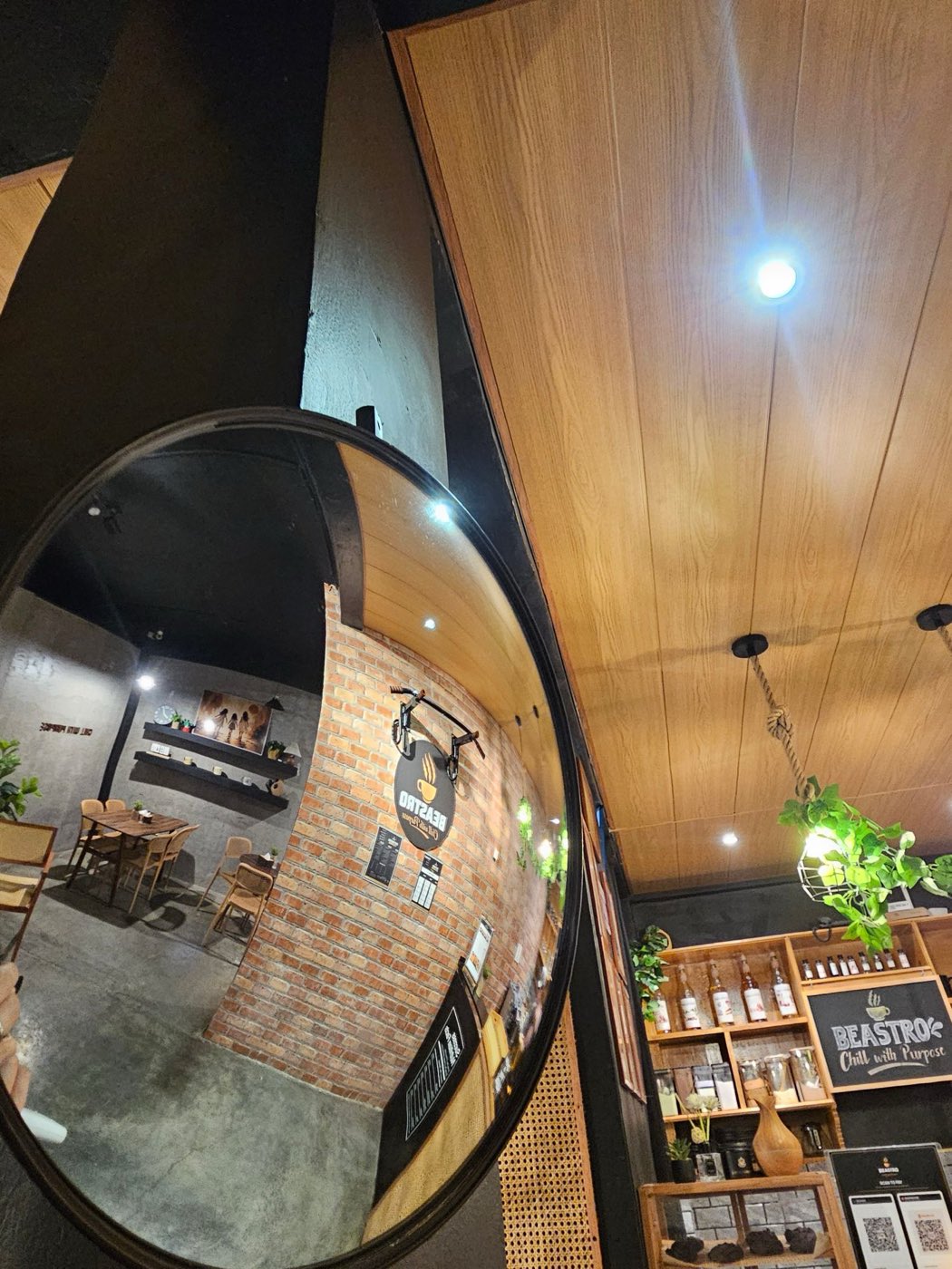 The round mirror reflecting the brick wall, pull-up bar and dining area under the wood ceiling